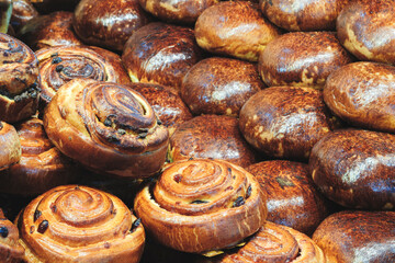 A stack of cinnamon rolls. The rolls are brown and have a spiral shape. There are many rolls in the stack