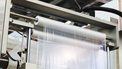 Automatic polyethylene plastic bag production machine with lighting effect. Close-up of the roller of the plastic bag production machine in the light blue scene. product packaging concept.