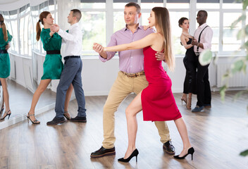 Fototapeta premium Active young woman training waltz in pair with man in dance-hall during dancing classes