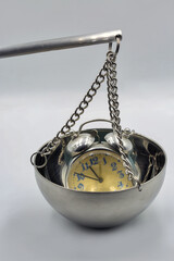 Alarm clock on metal balance scale closeup.