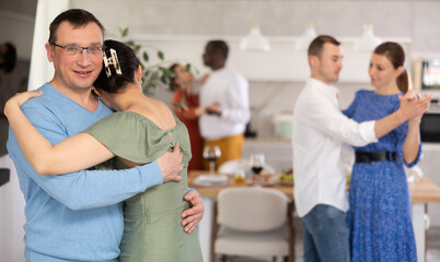 Multiethnic male and female couples slow dancing in kitchen