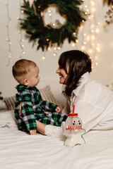 A mother in bed on Christmas morning with a boy in green pajamas. A bottle of milk is in front.
