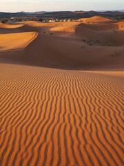 The play of light and shadow among the orange sand dunes of the Merzouga Desert at sunset. The texture of waves on the sand. Desert landscape. Travel to Morocco, Sahara Desert.