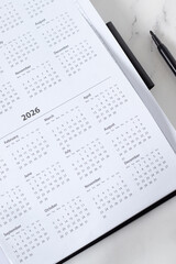 2026 new calendar year in notebook planner. Annual goals, business budget, strategy, aspirations, monthly schedule concept. Top view.