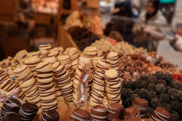 Colorful chocolate treats displayed at a market during a bustling afternoon