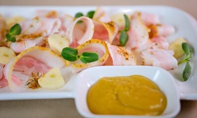 Meat appetizer with bread, onions and two sauces on a wooden board. Assorted meatloaf, lard and pate with mustard on a wooden serving board. lard with mustard