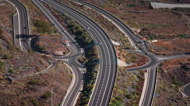 Tenerife, Canary Islands: Aerial view capturing cars driving along highway TF-1 through Tenerife's volcanic terrain, highlighting scenic infrastructure. Drone flight footage