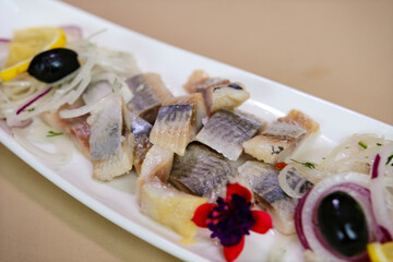Tasty sandwiches with herring, onions, lettuce and olives on white wooden table, closeup. High quality photo