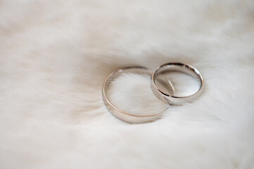 Two silver wedding rings shining on a soft white surface. Symbol of love, marriage and fidelity, perfect for wedding and jewelry themes, selective focus