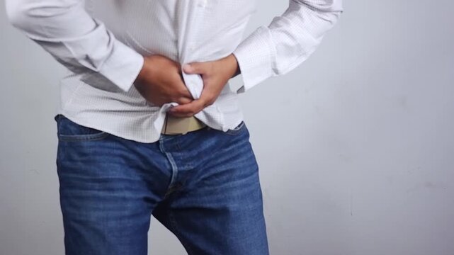 Stomach cramps, stomach aches, and other stomach ailments. A man's hands wrapped around his stomach indicate unbearable pain and injury in the abdominal area. Holding in a bowel movement.
