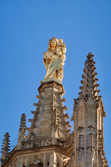 Majestic Golden Religious Statue atop Ornate Gothic Cathedral Tower Against Clear Blue Sky in Bordeaux, France – Captivating Architectural Details