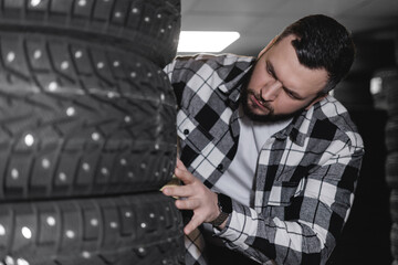 Young caucasian male chooses winter car tires in auto workshop store