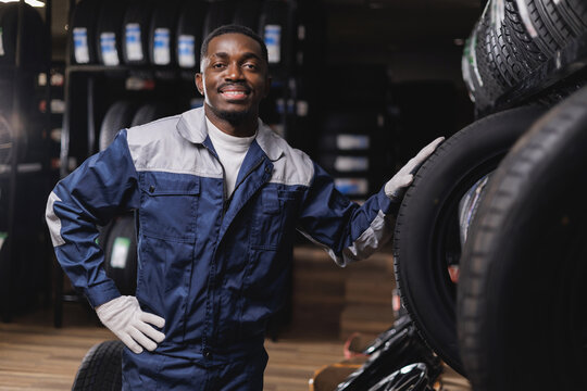 Tire at repairing service garage, Portrait happy African adult male mechanic smiling in tyre shop workshop
