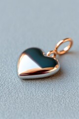 Metallic heart pendant on soft textured background, close-up, copy space