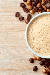 Top view cup of creamy coffee with roasted beans on wooden background, copy space