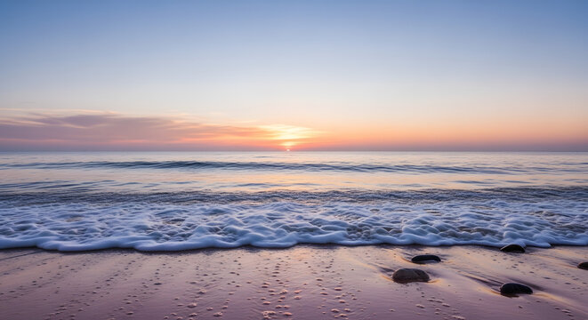 Ethereal seascape at daybreak showing the soft pastel colors of dawn with gentle waves washing over the sandy