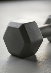 Single gray dumbbell rests, showcasing texture and form with smooth light