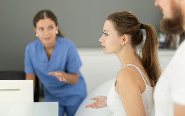 Fototapeta premium Dental clinic administrator talks to patients at the reception desk