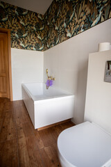 Intimate bath area with floral decor, Serene corner featuring wooden door and floral wallpaper, Comfortable bathtub nook decorated with blossoms and subdued lighting ambiance
