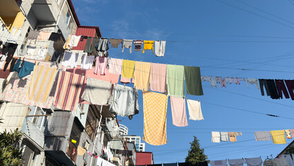 Colorful laundry hanging on multiple clotheslines stretched high above a residential street,...