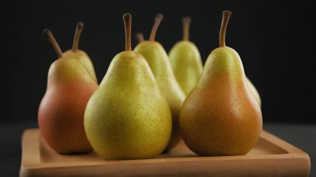Fresh pears arranged on a wooden tray. These succulent fruits are captured in a close-up shot, highlighting their natural textures and colors