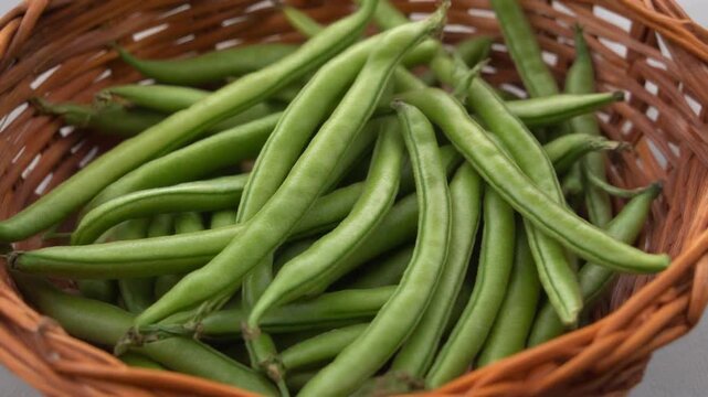 Fresh green beans displayed in a woven basket. The green beans are vibrant and look delicious, promising a healthy and tasty meal.