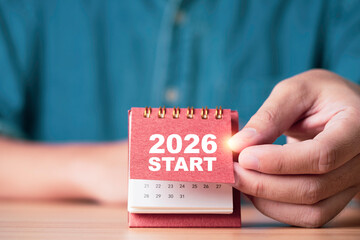 Hand flipping a calendar to reveal 2026 START symbolizing new beginnings future planning goal setting motivation and business strategy for corporate projects personal development and creative content.