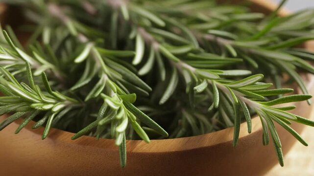 Fresh rosemary sprigs in a wooden bowl