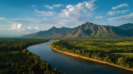 Fototapeta premium Aerial view captures winding river flowing through lush green valley bordered by imposing mountain range