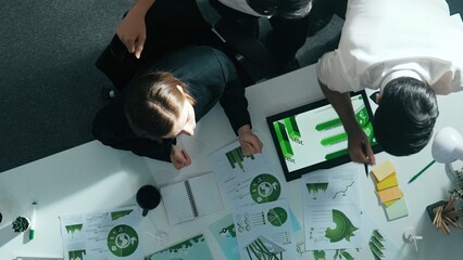Top down view of business team discussing about renewable energy. Aerial view of skilled diverse business people working together to plan about zero waste while using laptop on table. Alimentation.