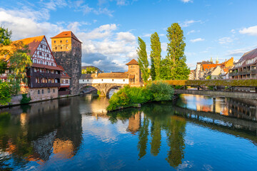 Fototapeta premium Historic Old Town. Weinstadel Building, Henkerbrucke and Maxbrucke Bridge, Henkerturm Tower on Summer Sunny Evening. Pegnitz River. Reflection in Water. Nuremberg, Franconia, Germany