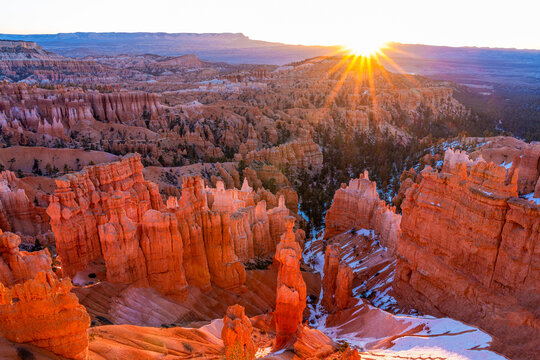 Bryce Canyon, Utah, at sunrise. Sunrise over the horizon at Bryce Canyon National Park, Utah. Characteristic hoodoo rock formations are glowing orange in the sun.