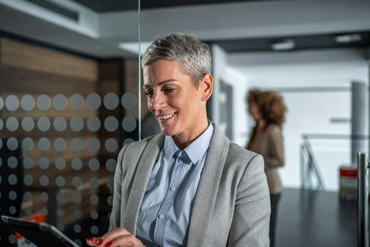 Mature businesswoman using tablet in modern office - Powered by Adobe