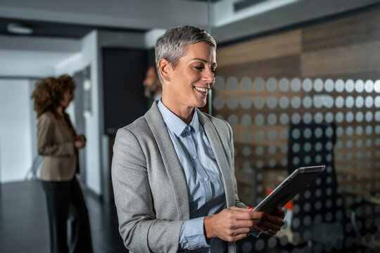 Mature businesswoman smiling and using a digital tablet enjoying work