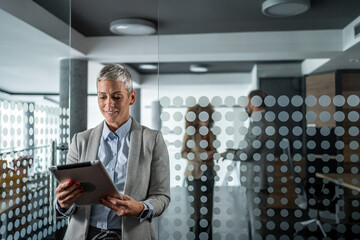 Businesswoman using digital tablet standing in modern office