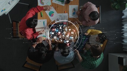 A diverse group of professionals collaborates in a modern office environment, using data visualization and analytical tools to strategize on projects while engaged in discussions. Raster