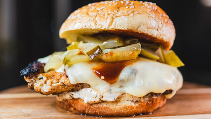Succulent chicken breast burger on brioche bun with cheese, pickles, homemade mayo and barbecue sauce. Healthy, protein-rich meal perfect for fitness and balanced diets.