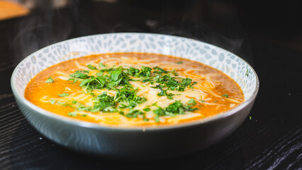 Thick vegetable soup with tender meat, melted cheese, and fresh parsley on top. Hearty, comforting, and perfect for cold days. Homemade and nutritious.