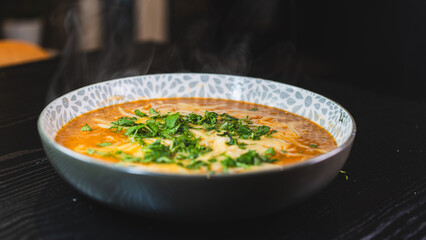Thick vegetable soup with tender meat, melted cheese, and fresh parsley on top. Hearty, comforting, and perfect for cold days. Homemade and nutritious.