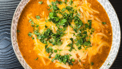 Thick vegetable soup with tender meat, melted cheese, and fresh parsley on top. Hearty, comforting, and perfect for cold days. Homemade and nutritious.