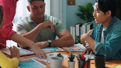 Top view of business people working together to choosing color from color palette. Project manager present idea by using tablet to marketing team while business man looking at logo graphic. Symposium.
