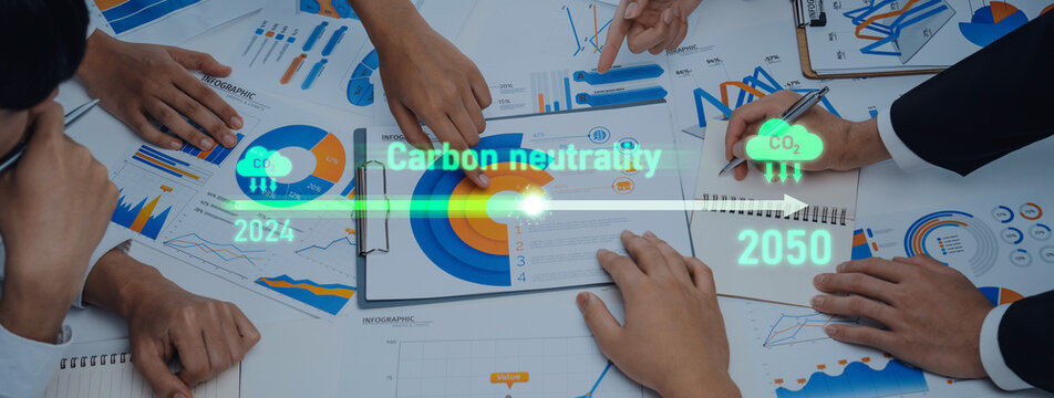 A team engages in a dynamic discussion about carbon neutrality goals set between 2024 and 2050. Data visualization aids focus on strategies and environmental sustainability. Trope