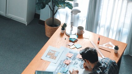 Top view of smart civil engineer looking project plan at meeting table while design building...