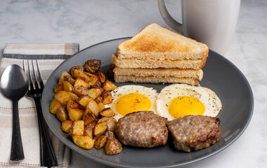 fried eggs served with sausage patties and home fries