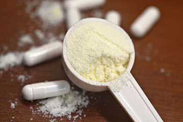 Measuring spoon with protein powder and nutrition tablets on a wooden background. Sports nutrition and health concept.