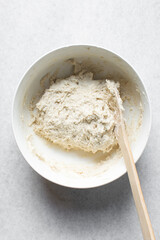 Overhead view of artisan bread dough being mixed in a white bowl, process of making bread dough