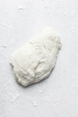 wet bread dough on a marble surface, flour covered sticky dough on a table, high hydration dough being kneaded on marble table