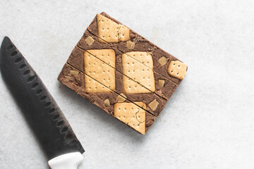 Overhead view of sliced chocolate fudge on marble countertop, top view of chocolate fudge topped with cookies and pieces of caramel chunks