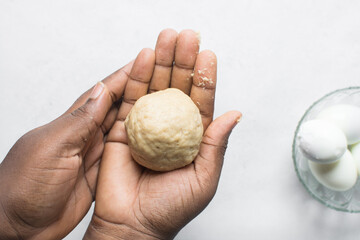 Egg being wrapped in dough to make nigerian egg roll, process of making nigerian egg roll and small chops