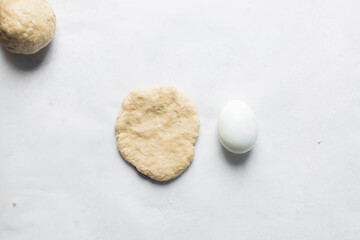 Egg being wrapped in dough to make nigerian egg roll, process of making nigerian egg roll and small chops
